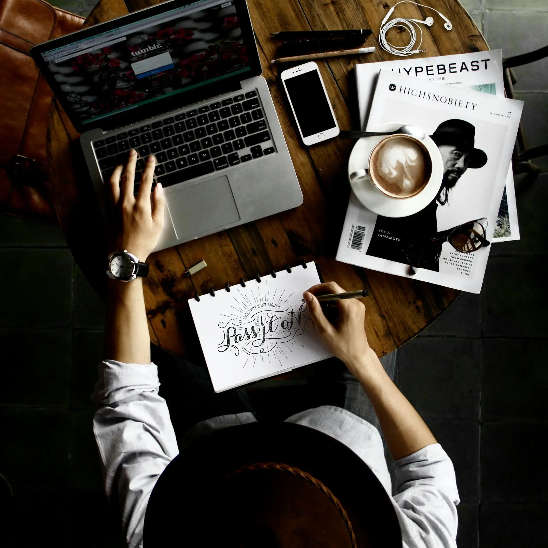 a woman scrolling on a laptop while writing on a book